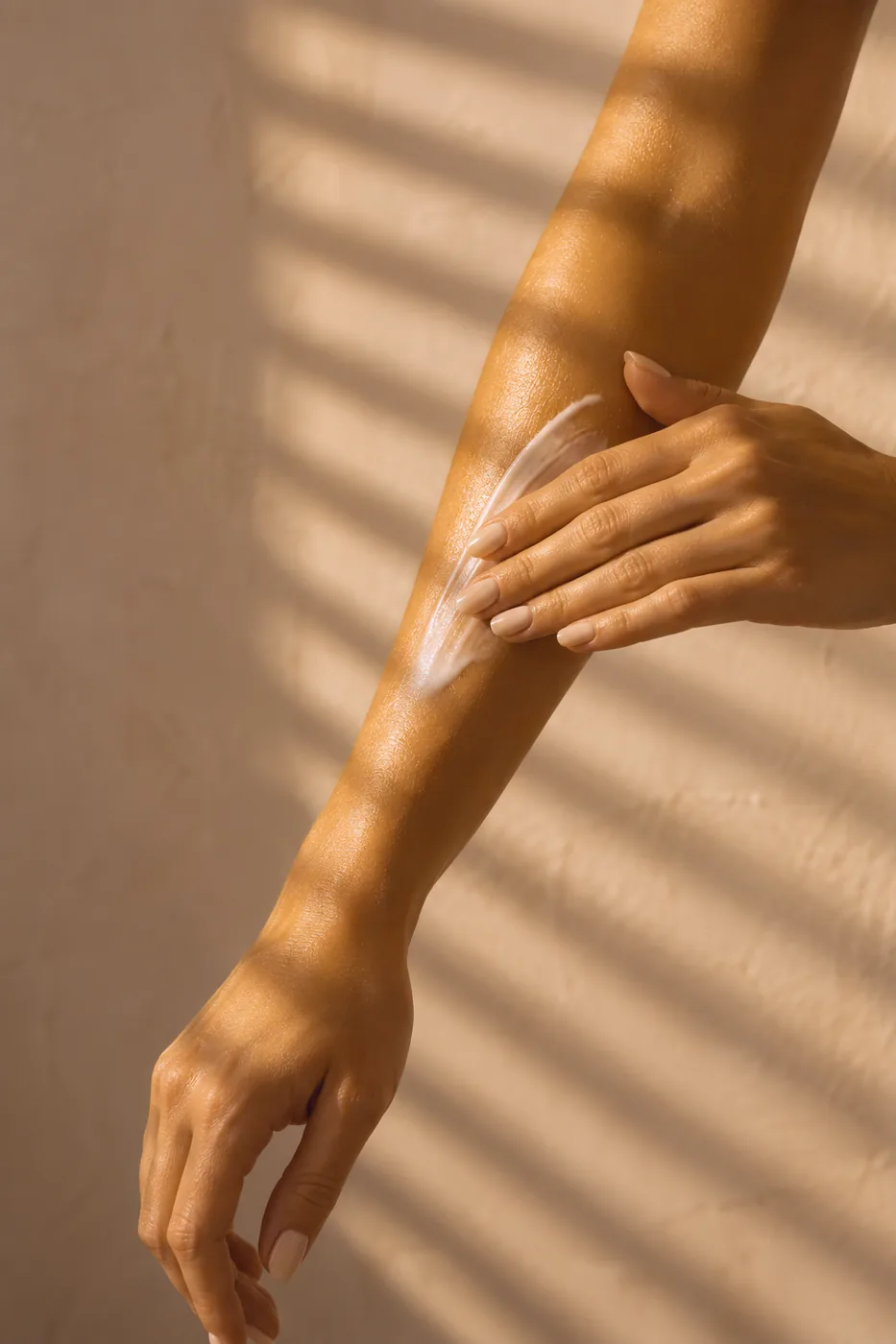 Testápoló felvitele az alkarra, zsalus árnyékkal a bőrön - a spray tan utáni ápolás mozdulata